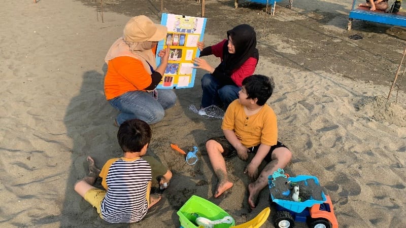 A person and children sitting on the sandAI-generated content may be incorrect.
